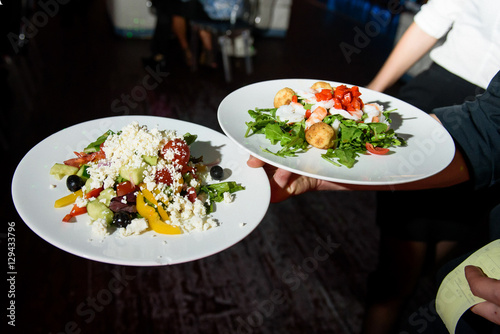 Fototapeta Naklejka Na Ścianę i Meble -  Round white plates with salads on waiter's hand