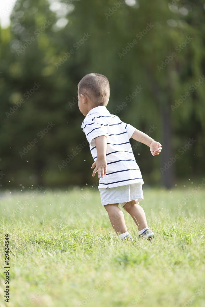 Happy Chinese baby boy jumping in meadow Happy Chinese baby boy jumping in meadow