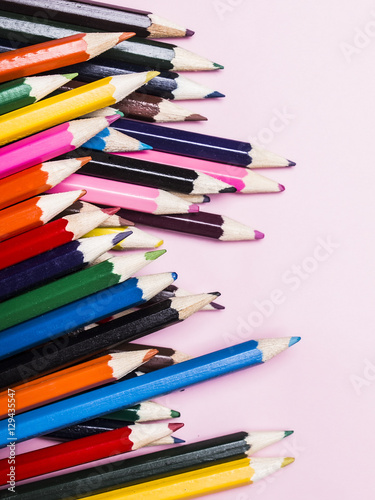 Set of colored pencils for drawing on a pink background.