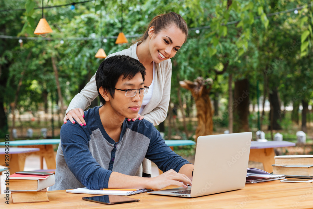 Couple using laptop tohether in outdoor cafe Couple using laptop tohether in outdoor cafe