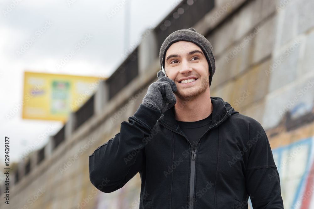 Happy young man talking on cell phone and smiling outdoors Happy young man talking on cell phone and smiling outdoors