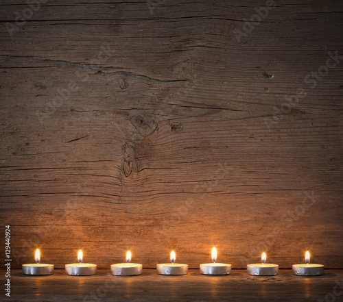 burning candles on the background of old barn boards