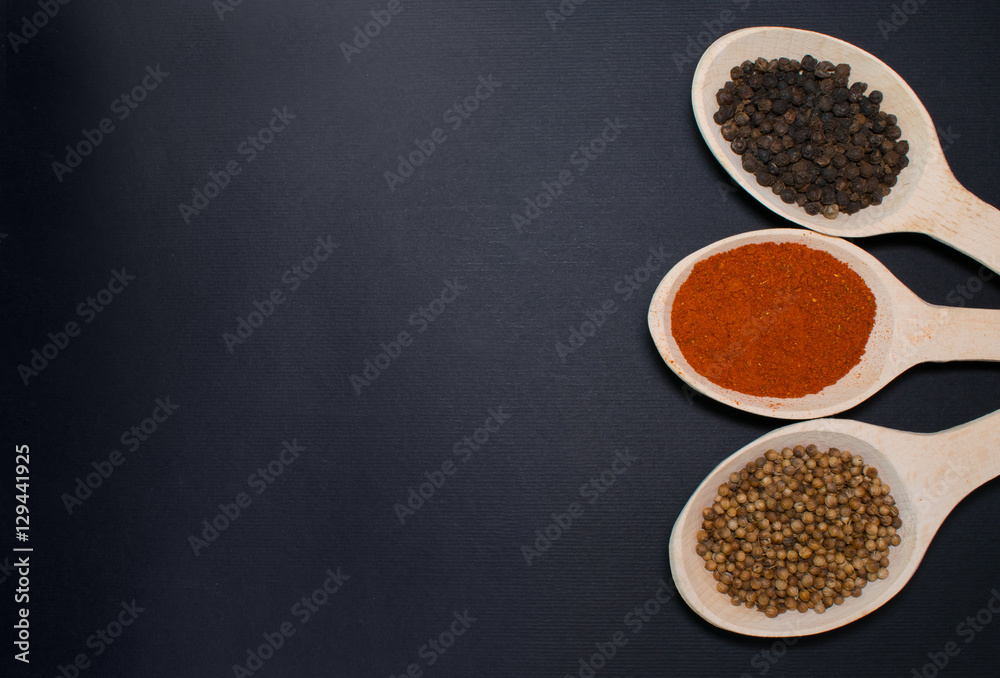 Wooden spoons with spices on black background Wooden spoons with spices on black background