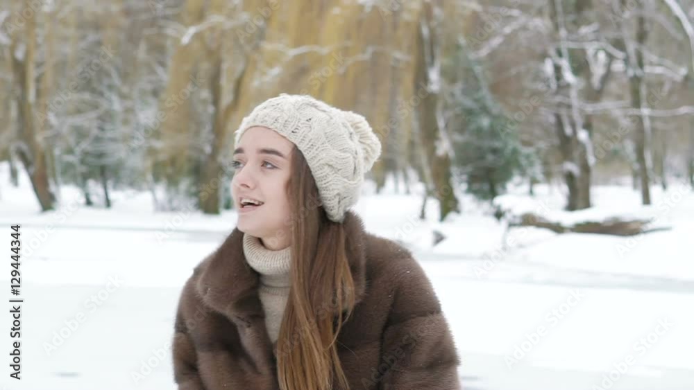 Happy young girl throwing up snow and laughing in the park. Slowly Happy young girl throwing up snow and laughing in the park. Slowly