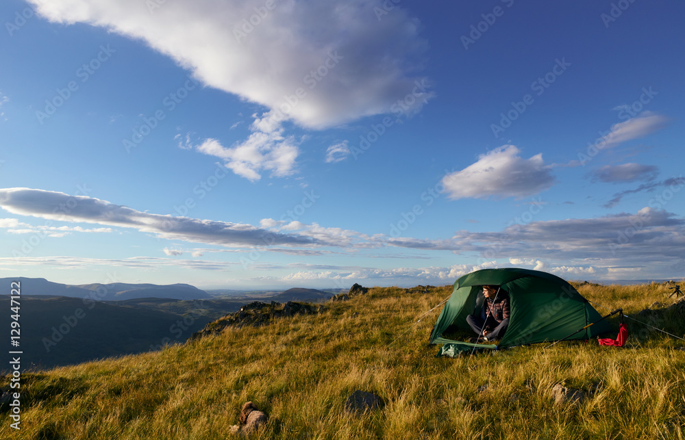 A hiker camping on the mountain summit of Place Fell in the Lake
