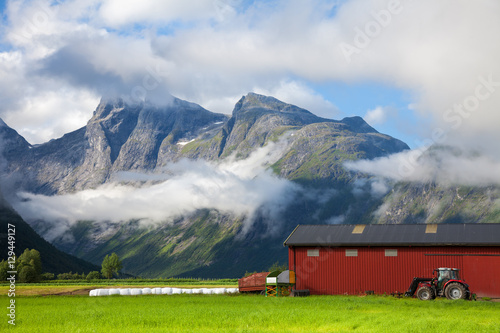 Small farm in Norway with tractor standing by a red barn wall
