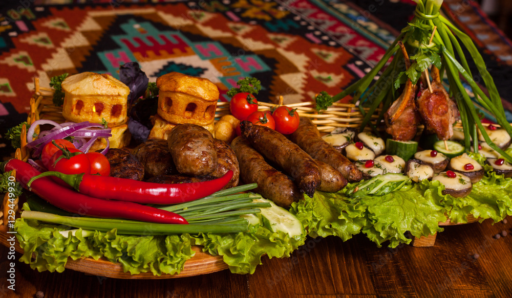 Homemade sausages, cutlets and baked potatoes with cheese with fresh vegetables and bread on a wooden tray