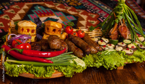 Homemade sausages, cutlets and baked potatoes with cheese with fresh vegetables and bread on a wooden tray
