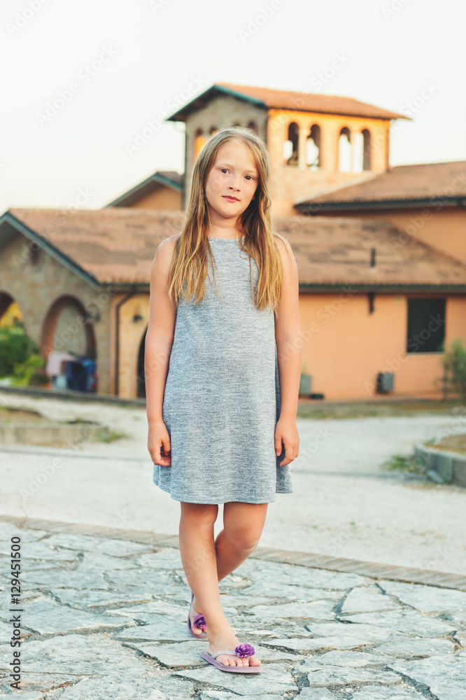 Summer portrait of 8-9 year old little girl wearing grey dress and