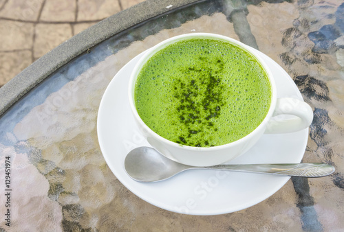 Closeup a cup of matcha latte or green tea on glass table backgr