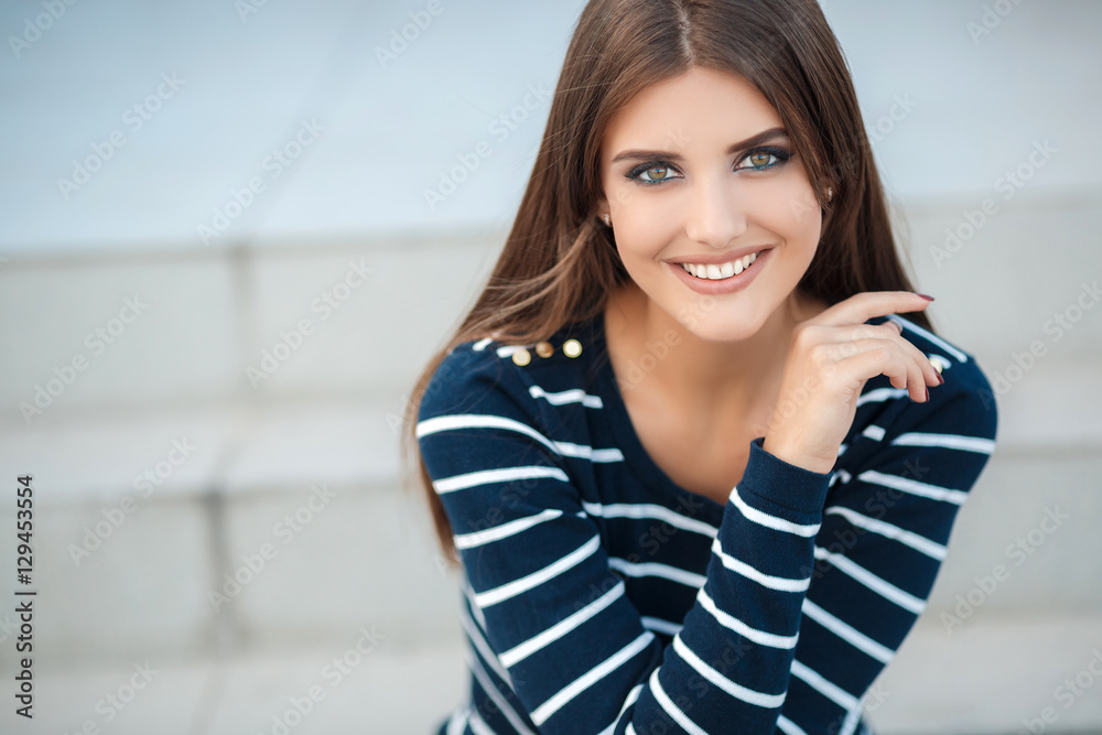 Portrait of a happy woman with long straight hair and gray-green eyes,nice smile,white straight teeth,dressed in a dark pullover with white stripes posing on a city street,sitting on the steps Portrait of a happy woman with long straight hair and gray-green eyes,nice smile,white straight teeth,dressed in a dark pullover with white stripes posing on a city street,sitting on the steps