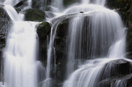 Beautiful view of the waterfall in the beech forest in the golden autumn season.