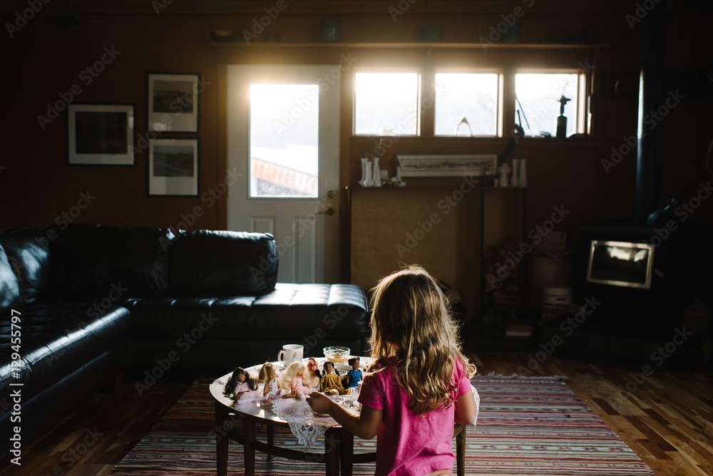 Young girl playing with dolls in living room, rear view Young girl playing with dolls in living room, rear view
