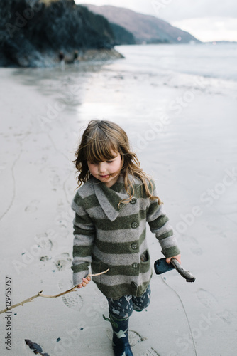 Girl holding stick in hand while walking on beach