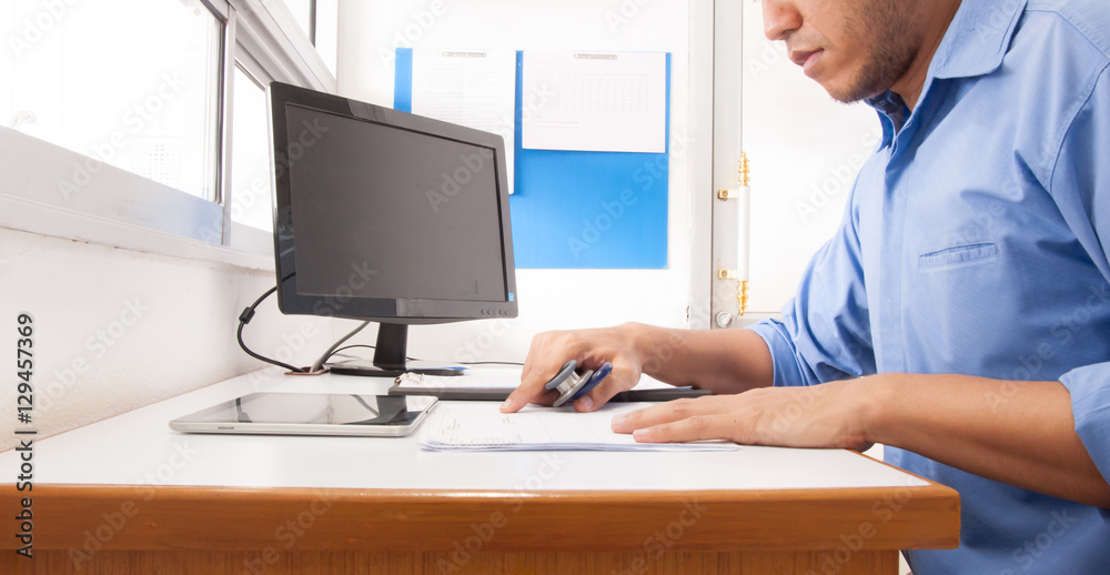 Doctor working at desk in the hospital with his computer.