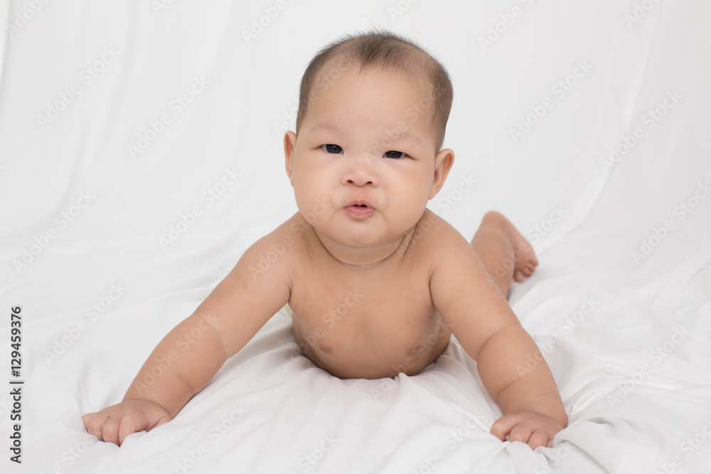 smiling surprised baby lying on a white bed. Baby born in Thailand, Asia. Infants aged 5 months smiling surprised baby lying on a white bed. Baby born in Thailand, Asia. Infants aged 5 months