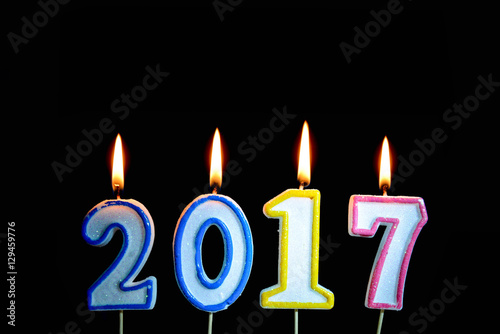 Colorful of year 2017 candle with flame lighting on the black background