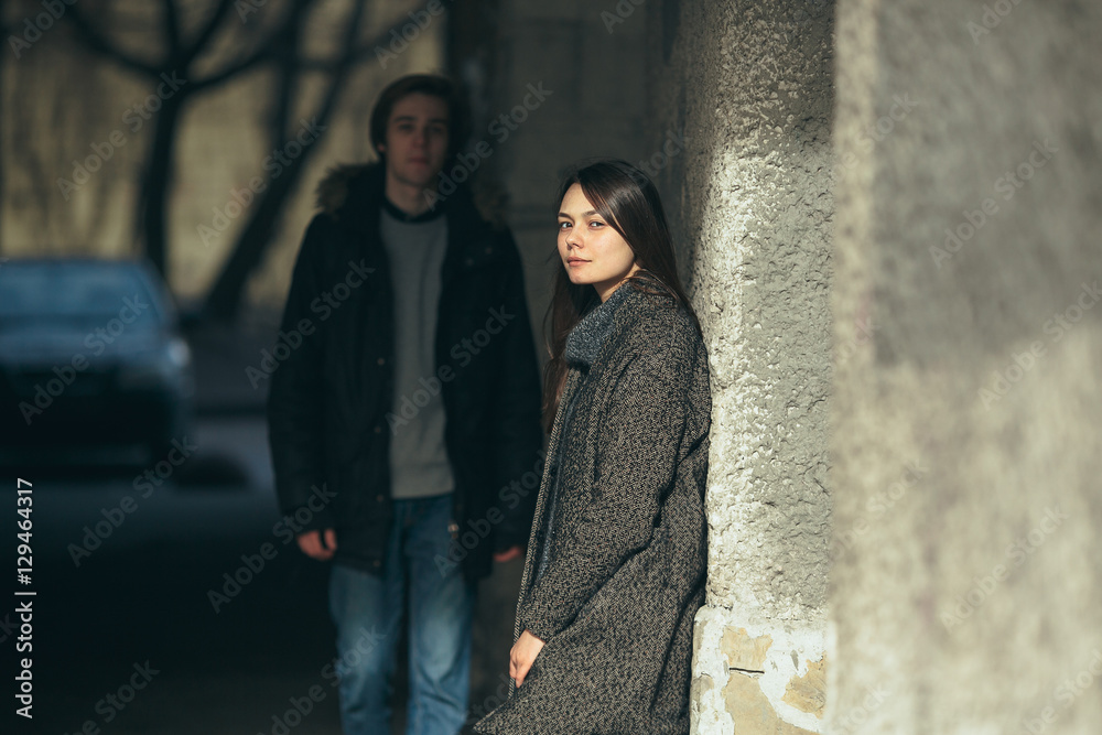 young couple standing together in front of wall