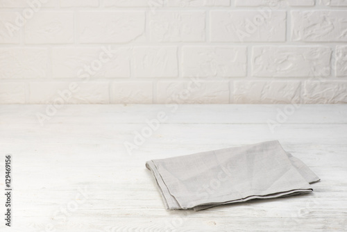 Fototapeta Naklejka Na Ścianę i Meble -  Gray napkin isolated on white wooden table. Copy space. Brick wall background. Front view.
