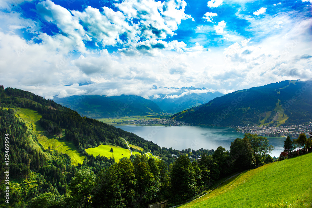 View over Zeller See lake. Zell Am See, Austria, Europe. Beautiful green meadows and pines at foreground, Alps at background.