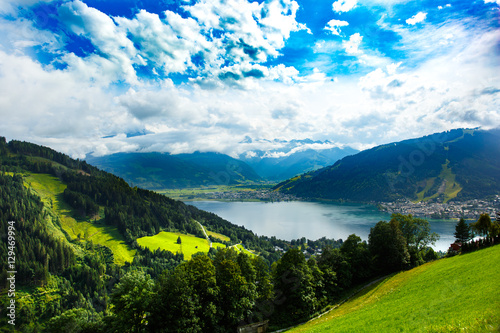 View over Zeller See lake. Zell Am See, Austria, Europe. Beautiful green meadows and pines at foreground, Alps at background.