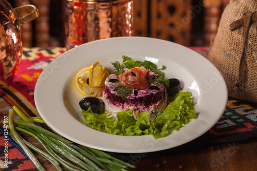 beet salad with red fish, herbs and olives on a white plate