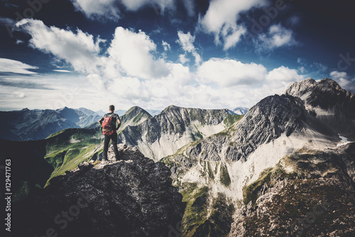 Mann steht auf einsamen Berggipfel in wilder Natur photo
