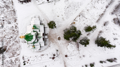 Aerial view at the wooden church in small Russian town. Winter season with snow on the earth © Kekyalyaynen