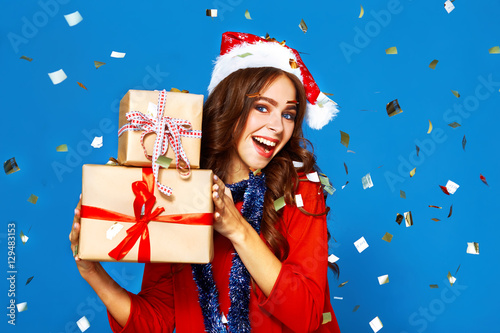 portrait of happy young lady in santa claus hat with gift make selfie .Christmas concept. in evening dresses on party over white background. firecrackers in the background. 