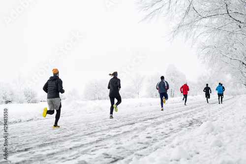 group young people running together snowy trail in winter Park. rear view