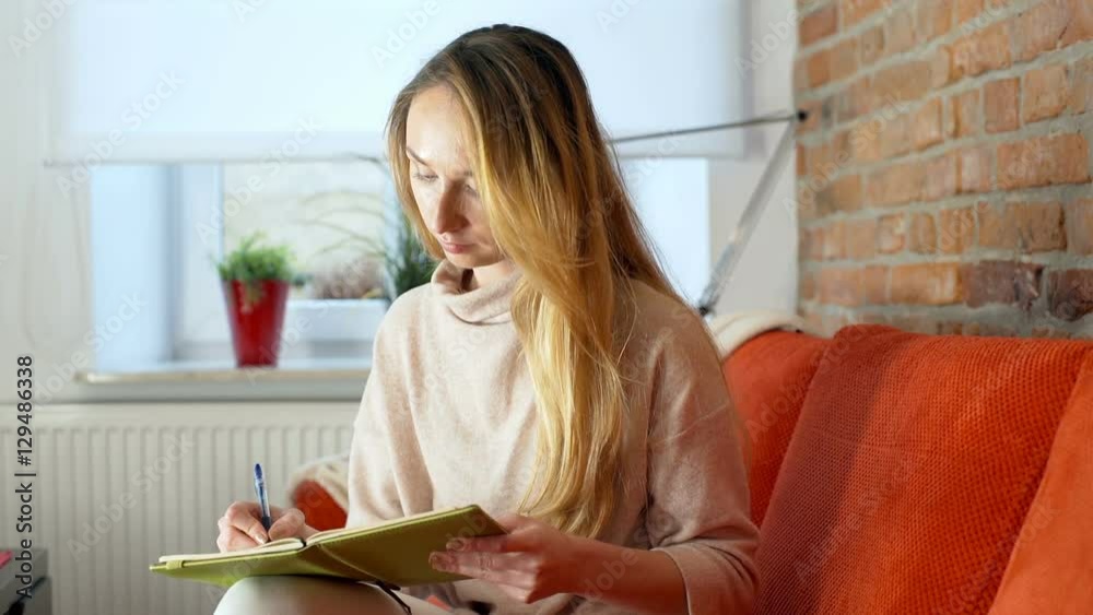 Absorbed girl sitting on the sofa and writing something in her notebook
Absorbed girl sitting on the sofa and writing something in her notebook