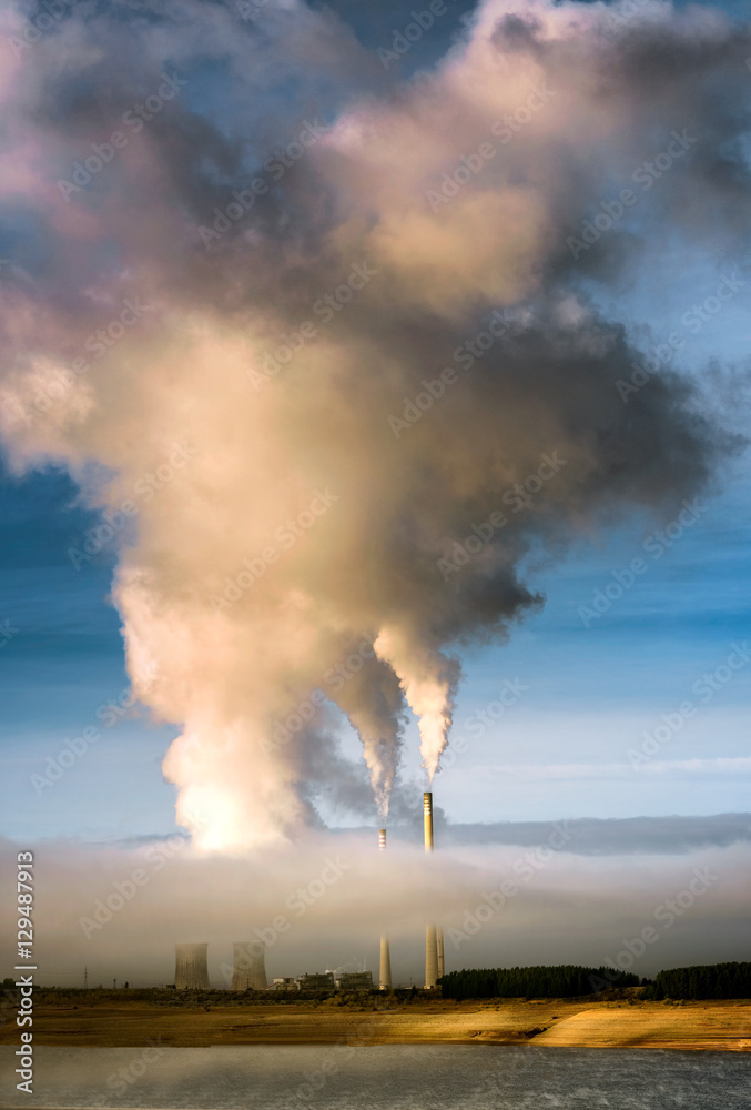 White smoke comes out of power plant that is partially hidden by morning fog White smoke comes out of power plant that is partially hidden by morning fog