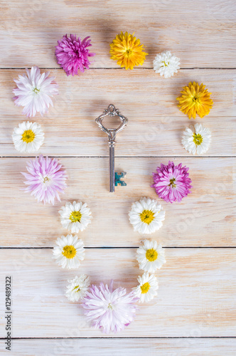 Flowers and key on wooden background. flat lay, top view