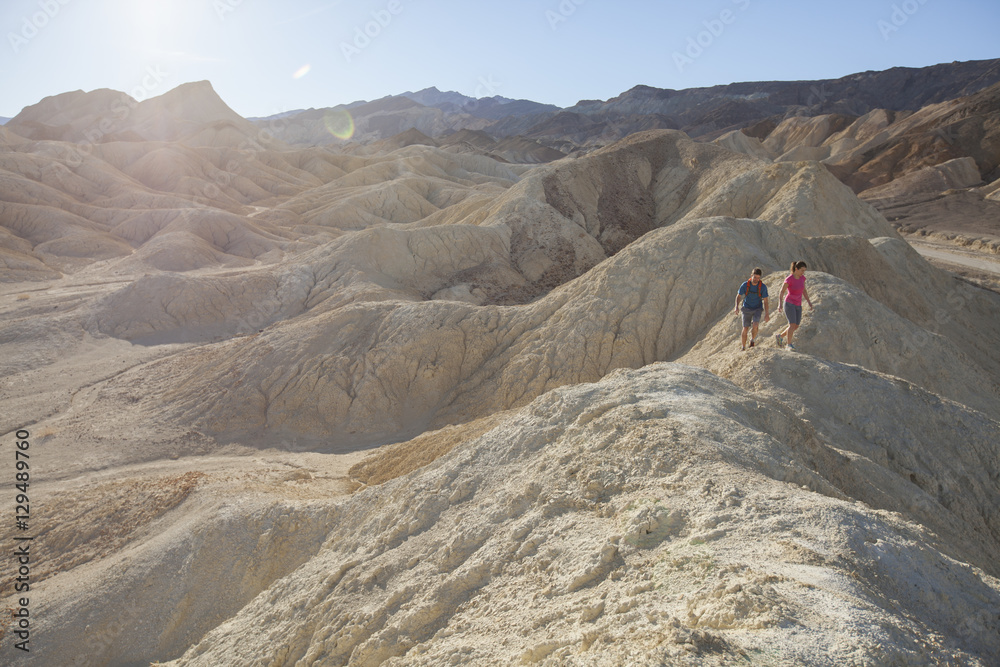 A man and woman hiking on the hilly, moon-like landscape of Death Valley.  California.