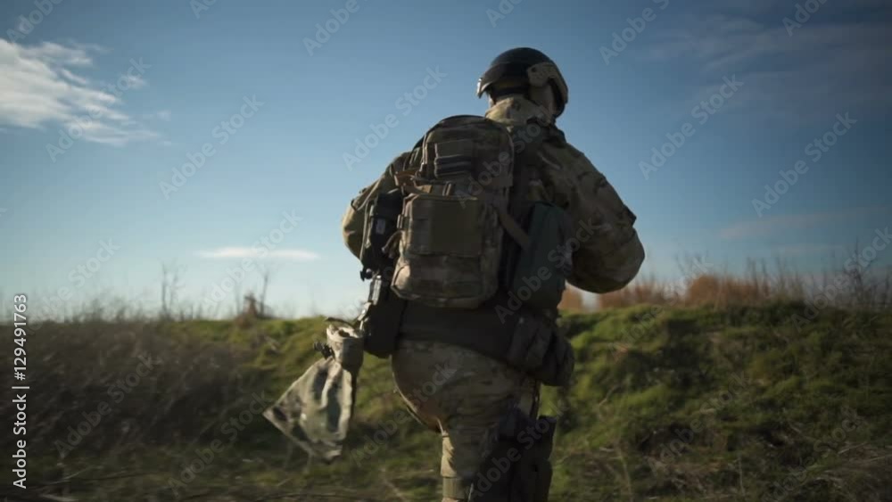 Airsoft soldier with a rifle and full NATO ammunition running and aiming