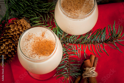Traditional Christmas alcoholic cocktail - Irish Cream, Cola de mono (monkey tail), decorated with cinnamon. Against the background of Christmas decorations on a wooden table. Copy space