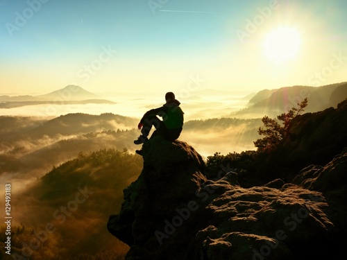Man tourist sit on exposed rock. View point with heather and branches photo