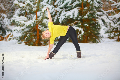 beautiful woman doing yoga outdoors in snow