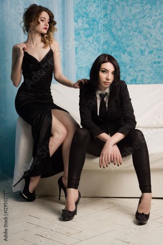 Two fashionable girls sitting on the armchair