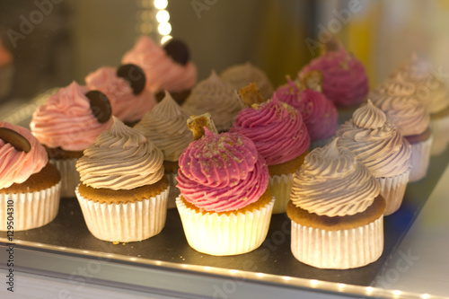 colorful cupcakes on a display in patisserie shop, street food in europe photo