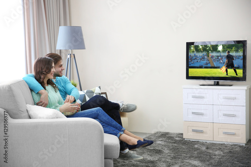 Young couple watching footb...