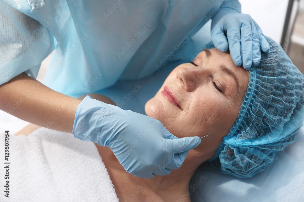 Surgeon operating female patient with scalpel at beauty salon Surgeon operating female patient with scalpel at beauty salon