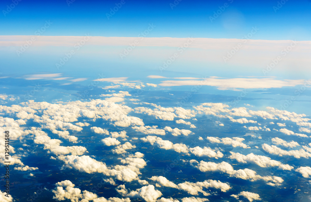 Fototapeta premium Fluffy white clouds and blue sky seen from airplane.