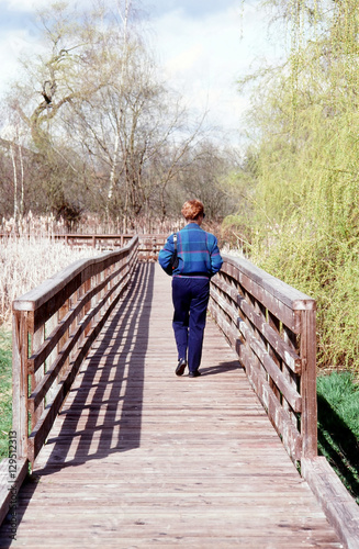 Mature female blond beauty walking on a bridge.