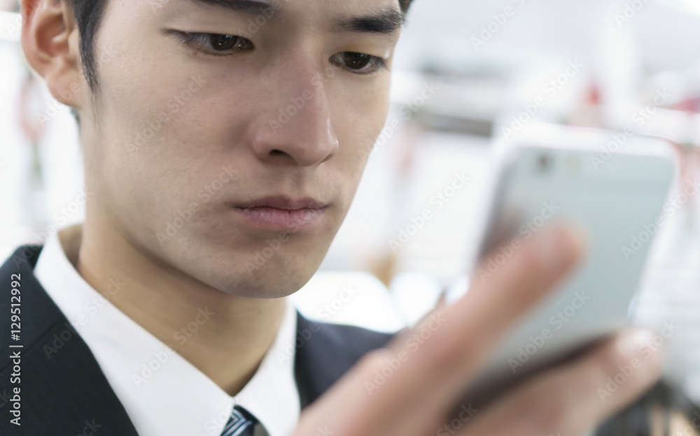 電車内でスマホを操作する男性 ビジネスマン 疲れ 疲れ目 険しい表情 電車内でスマホを操作する男性 ビジネスマン 疲れ 疲れ目 険しい表情