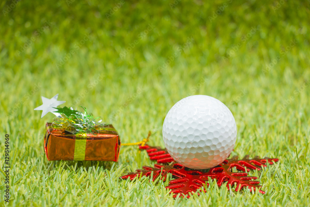 Naklejka premium Golf ball and Christmas ornament on green grass