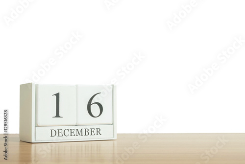 Closeup surface white wooden calendar with black 16 december word on blurred brown wood desk isolated on white background with copy space , selective focus at the calendar