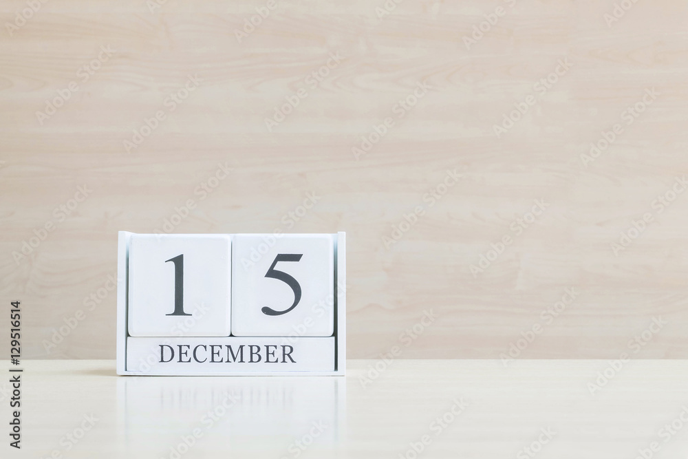 Closeup surface white wooden calendar with black 15 december word on blurred brown wood desk and wood wall textured background with copy space , selective focus at the calendar Closeup surface white wooden calendar with black 15 december word on blurred brown wood desk and wood wall textured background with copy space , selective focus at the calendar