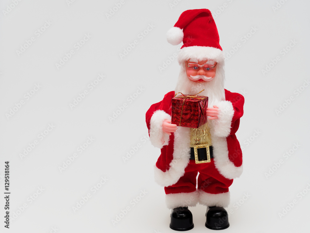 Toy Santa Claus holding a red gift box isolated on white background Toy Santa Claus holding a red gift box isolated on white background