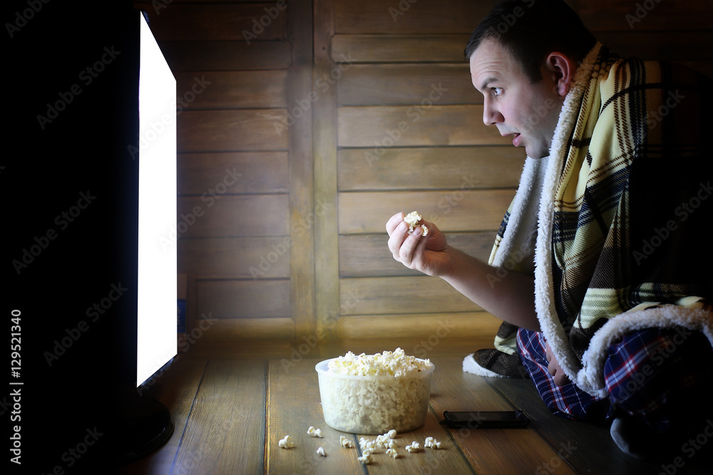 Naklejka premium young man watching television at home on the floor